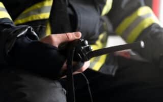 Firefighter holding a walkie-talkie, safety gear visible.