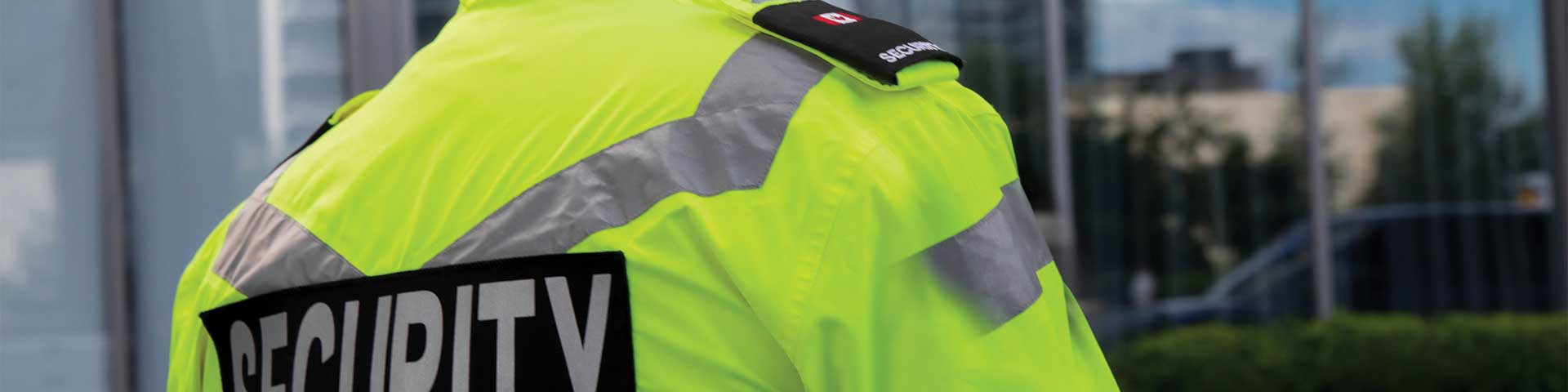 Security guard in high-visibility jacket outside building.