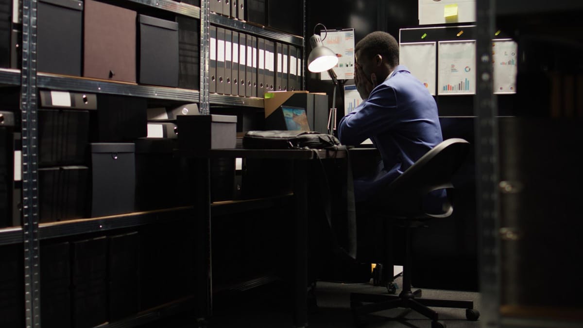 Why-Risk-Assessments-Are-the-First-Step-in-Security-Planning Person stressed at desk in storage room.