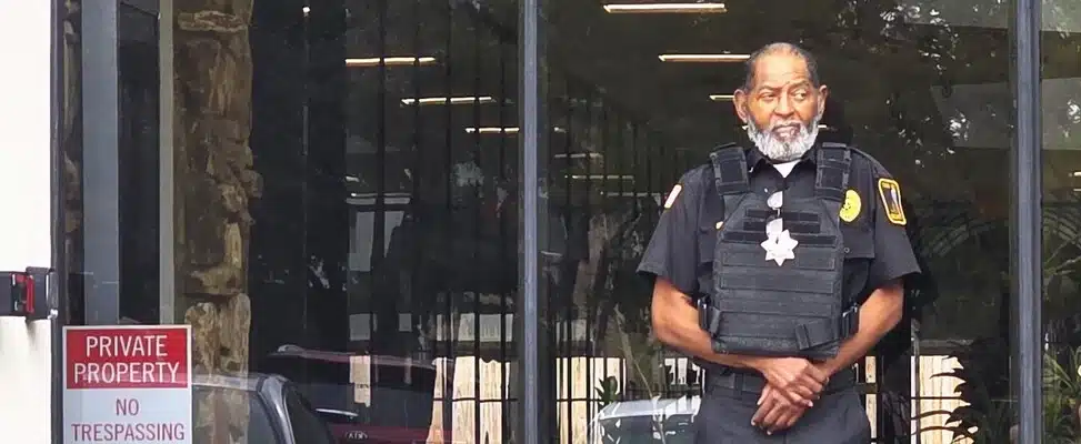 doorman-security-dallas-img-1 Security guard standing outside a building entrance.